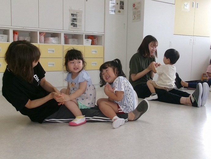 2歳児が保育者とわらべ歌遊びをしている写真
