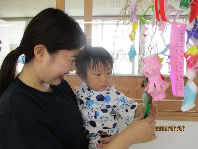 0歳児が笹飾りを保育者と見ている写真
