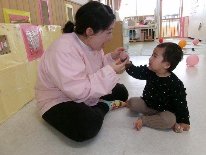0歳児が保育者と遊んでいる写真
