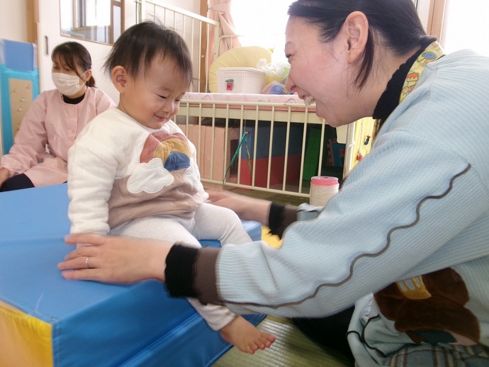 0歳児が保育者と遊んでいる写真
