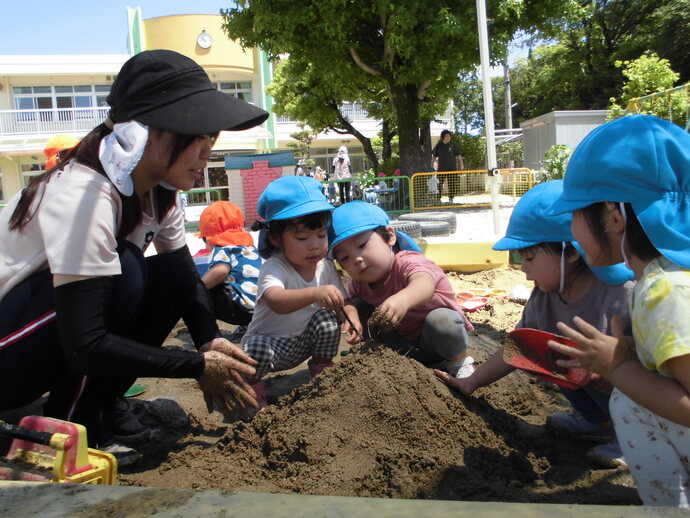 2歳児 友達と砂場で山を作っている写真