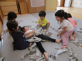 写真:2歳児達の新聞紙遊びの様子