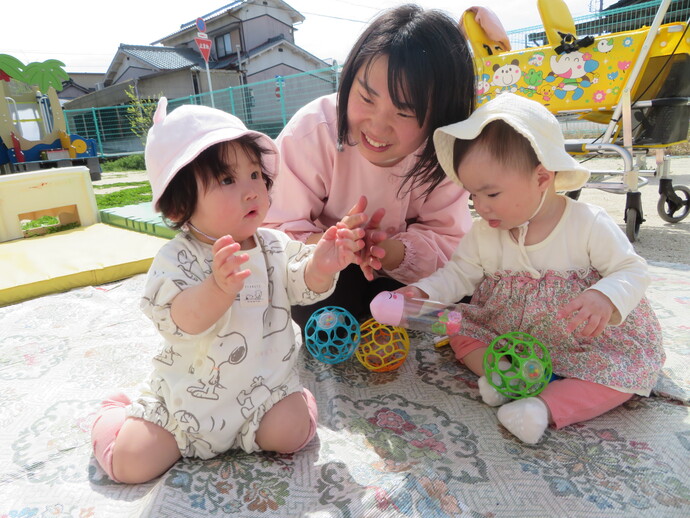 保育者と子どもが戸外で遊んでいる