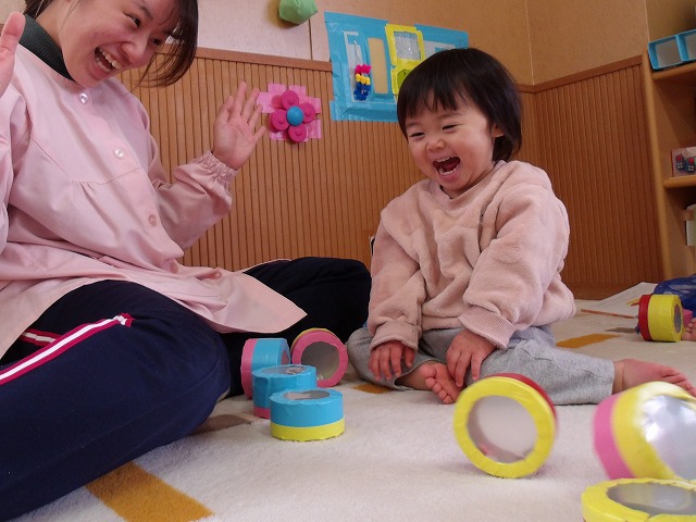 写真:先生と一緒に積んだ箱を倒して遊んでいる