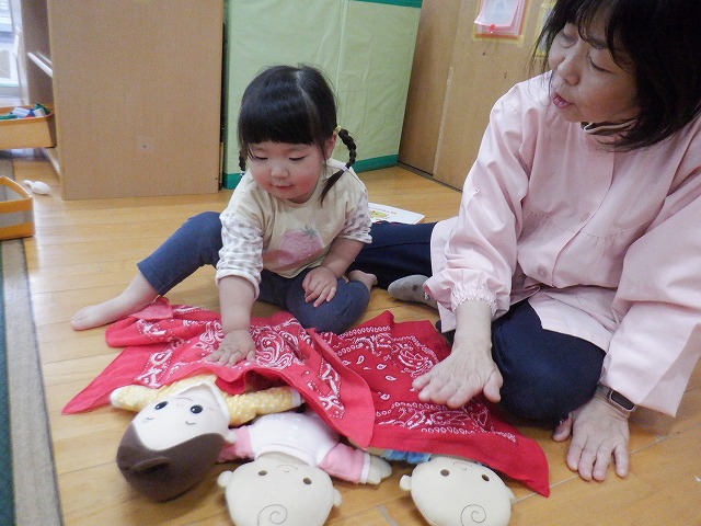 写真:保育者と人形を寝かしつけている様子