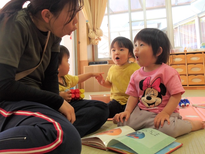 写真：保育者と絵本を読んでいる1歳児