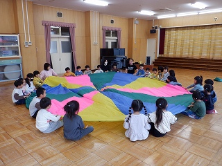 写真：年中児　直径3メートルほどの円形の布をクラス全員の子で持っている様子