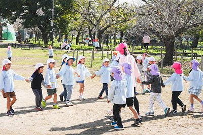 写真：年長児　秋の遠足で友達と花いちもんめをする様子